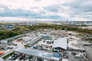 Luftaufnahme der Recyclinganlage der Cemex Heim RC-Baustoffe mit Hallen, Materiallagern und großen Schüttgut Halden am Stadtrand von Berlin